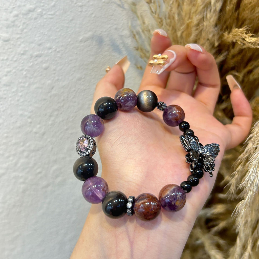 Close-up of Amethyst Phantom Quartz beads with butterfly charm and purple gemstone accent
