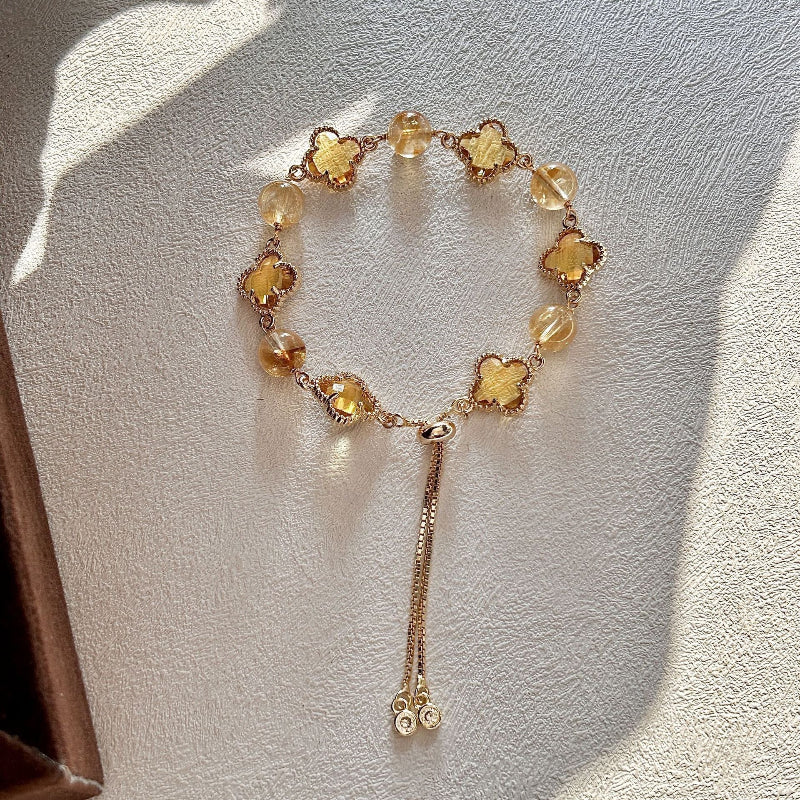 Woman wearing a Citrine and Golden Tiger's Eye four-leaf clover bracelet with elegant golden tones