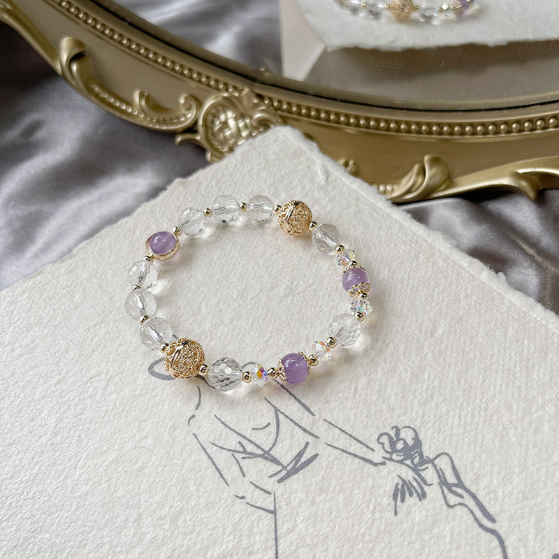 Close-up detail of a natural faceted clear quartz bracelet with purple jade beads and an antique-inspired copper orb charm.