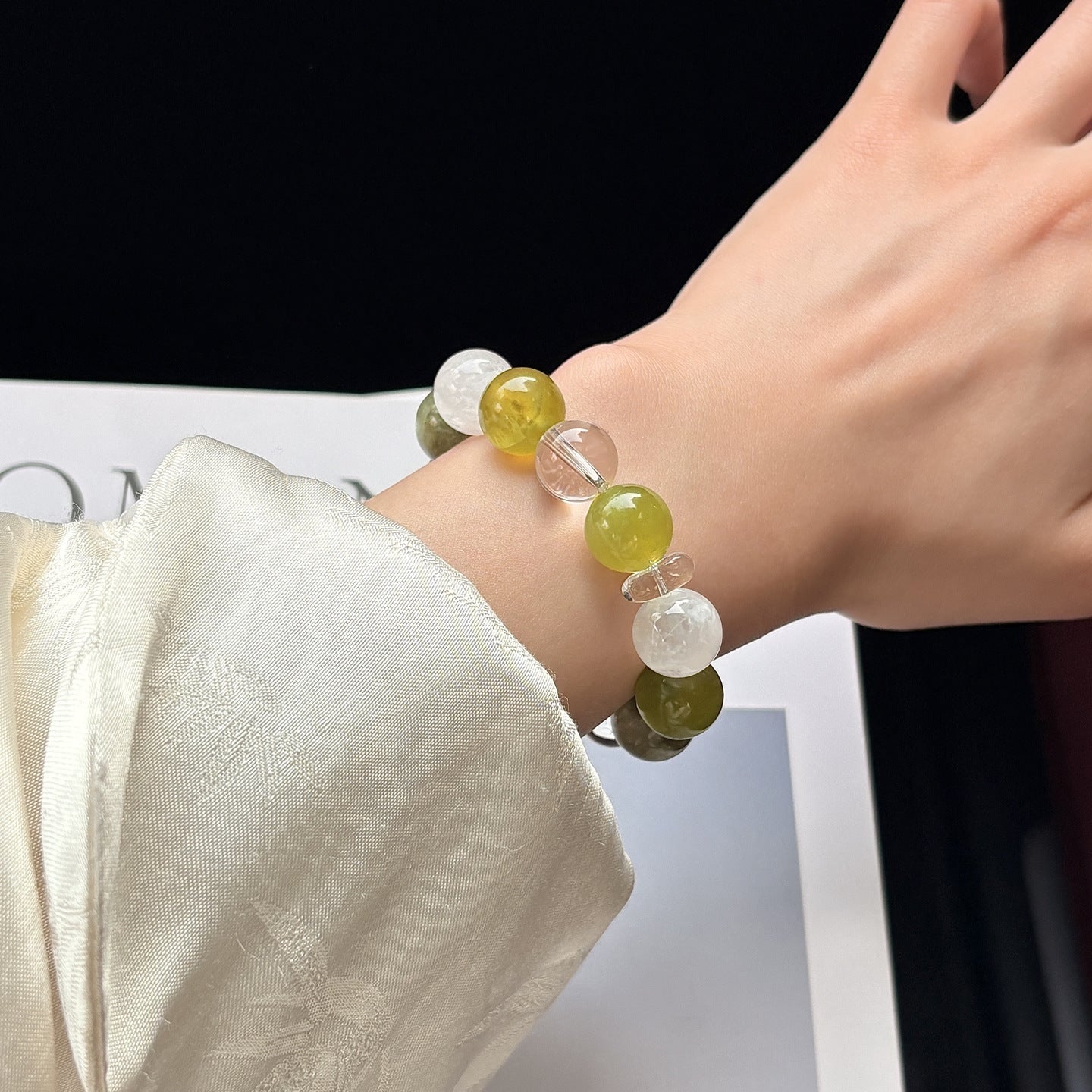 Woman wearing a natural green gemstone bracelet featuring Xiuyu Jade and Green Phantom Quartz